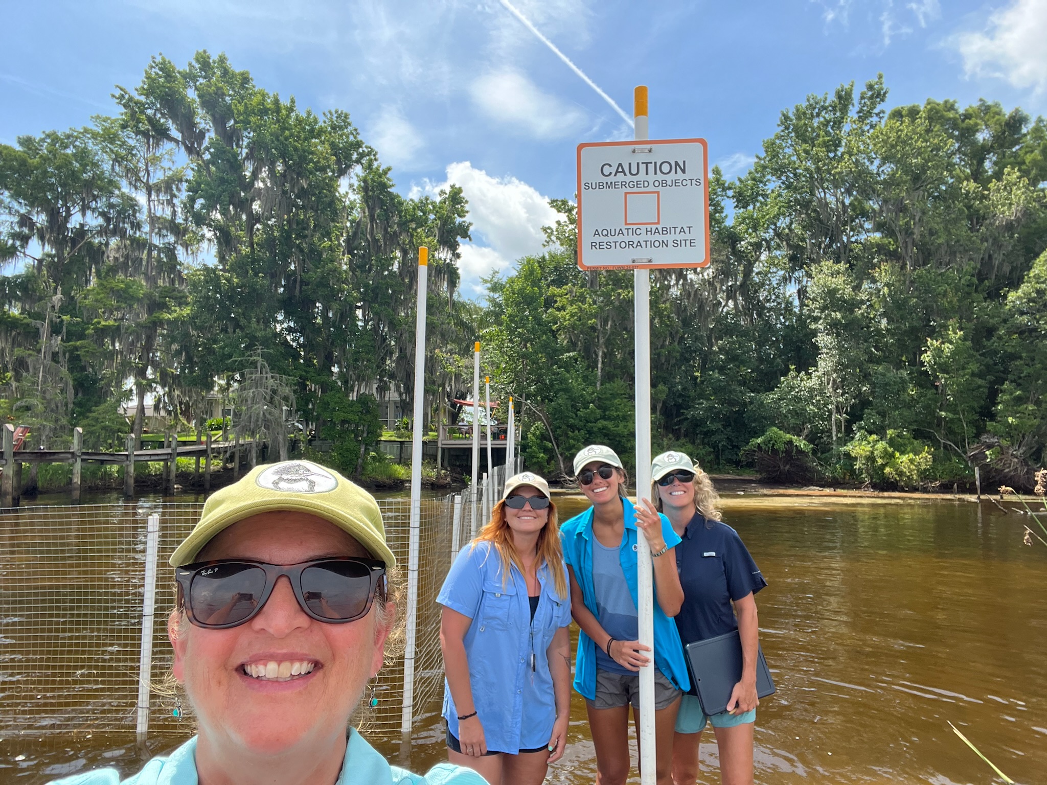Team near the newly installed enclosure and informational sign